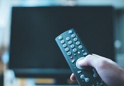 Hand pointing a TV remote to a fairly aw