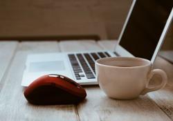 Mouse and cup of coffee by a laptop computer