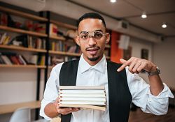 man pointing to pile of books