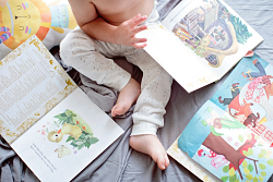 Baby sitting on blanket surrounded by books