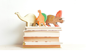 stack of children's books with toy dinosaurs