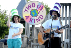 "Two of a Kind" logo and photo of husband-wife singing duo with guitars